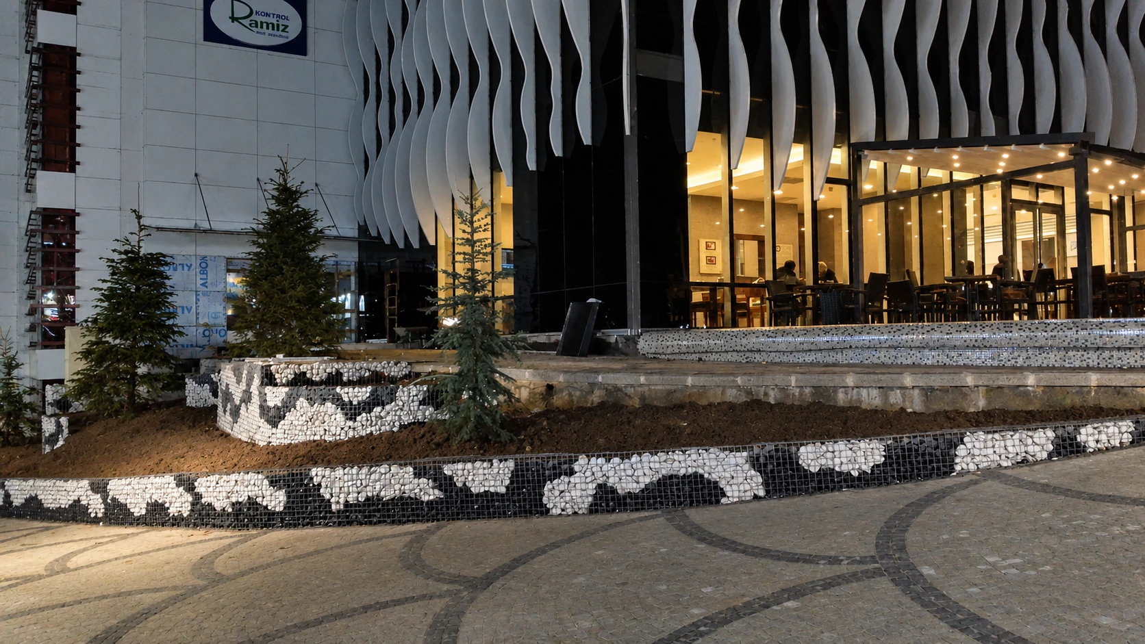 Plato AVM · Gabion Taş Duvarlı İstinat Tasarımı. Gabion duvarlar ve formlu çamlarla modern binaların giriş alanlarına güçlü bir karakter katıyoruz.